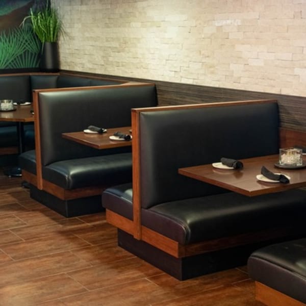 Mezcal Mexican Bar & Kitchen's dining area with dark leather booths, wooden tables, and a plant.