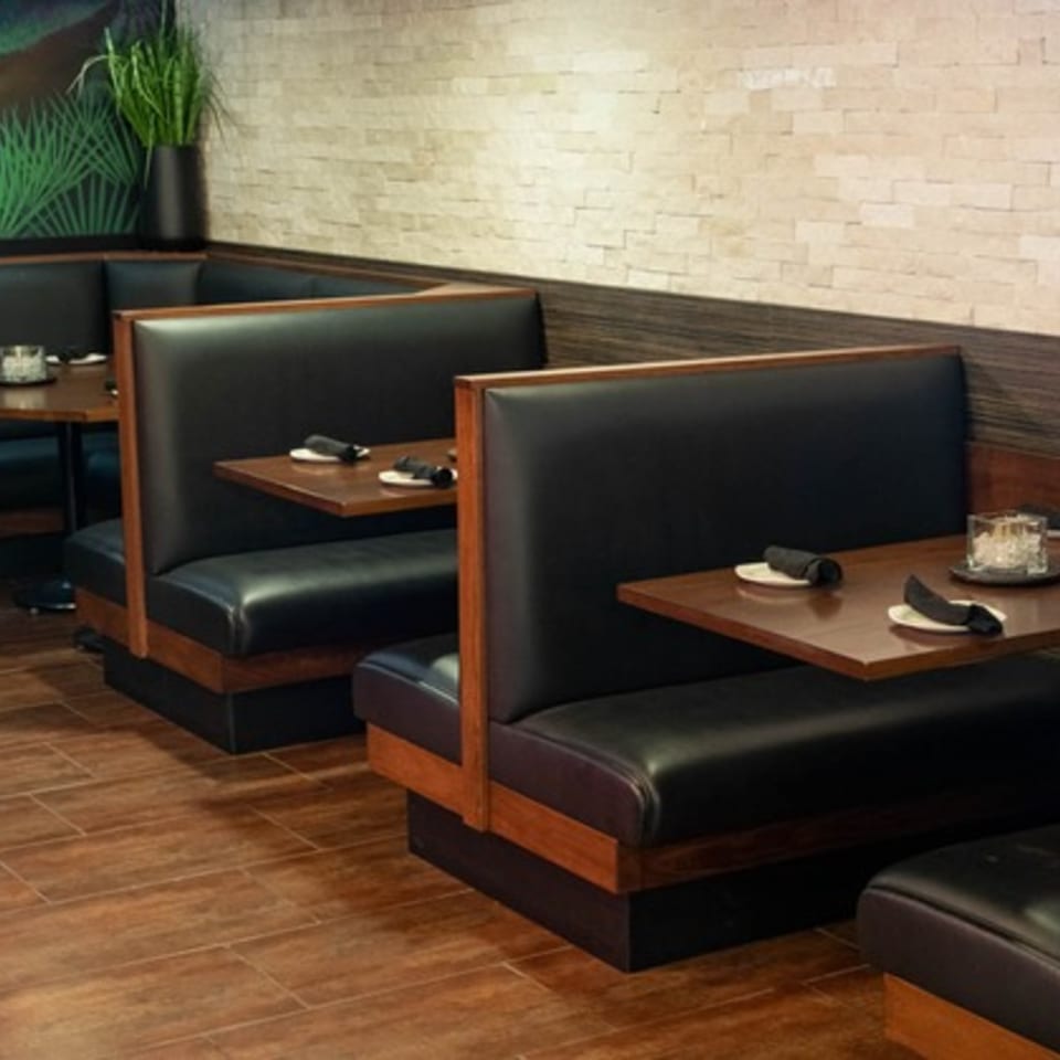 Mezcal Mexican Bar & Kitchen's dining area with dark leather booths, wooden tables, and a plant.