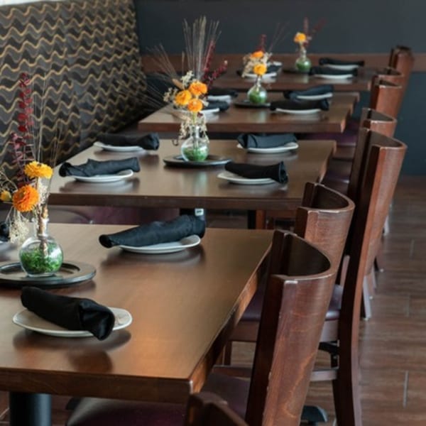 Dining room at Mezcal Mexican Bar & Kitchen with set tables, dark wood chairs, and decorative vases.