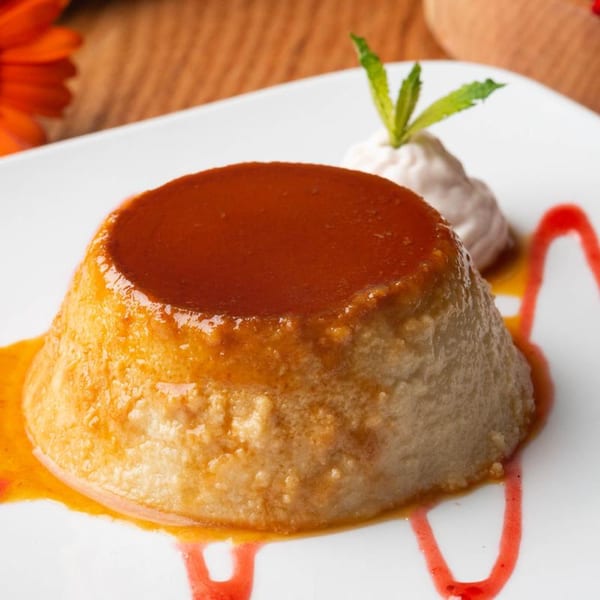 Mezcal's flan dessert, topped with caramel sauce, whipped cream, and a mint sprig.