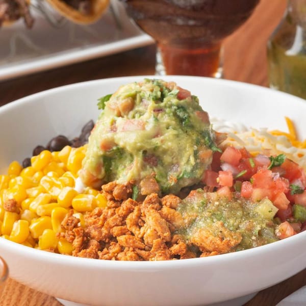 A Mezcal Mexican Bar & Kitchen burrito bowl with guacamole, corn, beans, chicken, and salsa.