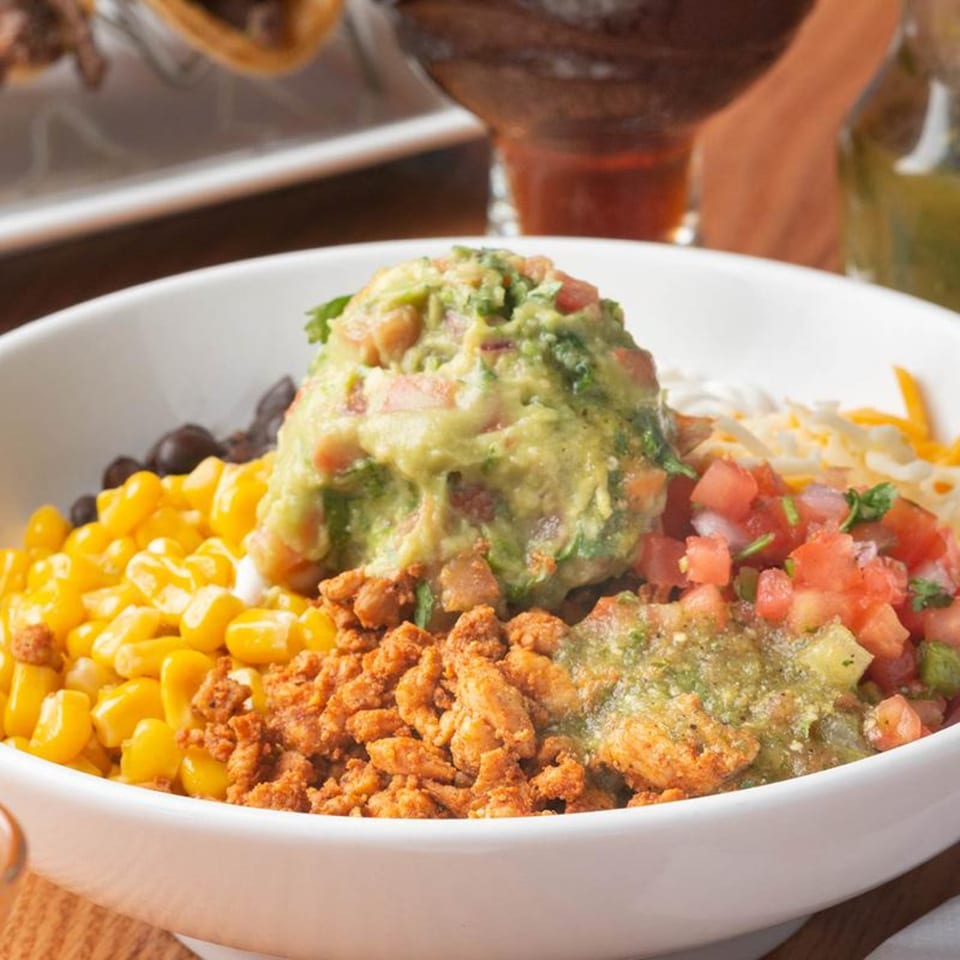 A Mezcal Mexican Bar & Kitchen burrito bowl with guacamole, corn, beans, chicken, and salsa.