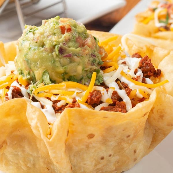 Mezcal's taco salad with ground beef, shredded cheese, sour cream, and a large scoop of guacamole.