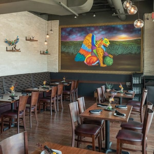 Mezcal Mexican Bar & Kitchen dining room with tables, chairs, and a large colorful mural.